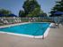 Inviting outdoor pool area with vibrant blue water, surrounded by comfortable lounge chairs and shaded by elegant blue umbrellas.
