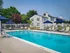 Inviting outdoor pool area with stylish lounge chairs and umbrellas, set against charming apartments and lush greenery.