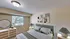 Tranquil bedroom with modern decor, featuring a plush green headboard, chic abstract art, and ample natural lighting.