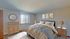 Inviting bedroom with a cozy bed, stylish side tables, abstract wall art, and a window offering natural light.