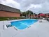 Inviting apartment outdoor pool area with sleek lounge chairs and vibrant red umbrellas, perfect for relaxation and leisure.