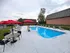 Inviting outdoor pool area with red umbrellas, elegant loungers, and relaxing seating, perfect for enjoyable summer days.