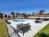 Inviting outdoor pool area with stylish wrought iron furniture and red umbrellas, perfect for relaxing and social gatherings.