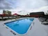 Inviting outdoor pool area with refreshing water, surrounded by red umbrellas and comfortable lounge chairs for relaxation.