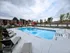 Inviting outdoor pool area with sleek lounge chairs and vibrant red umbrellas, perfect for relaxation and recreation in a serene residential community.