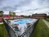 Inviting outdoor pool area with vibrant red umbrellas, surrounded by comfortable seating and lush greenery, perfect for relaxation and social gatherings.