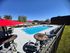 Inviting outdoor pool area with vibrant red umbrellas, stylish patio furniture, and a spacious sun deck for relaxation.