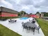 Charming apartment complex featuring a well-appointed outdoor pool area with elegant seating and vibrant red umbrellas, perfect for relaxation and social gatherings.