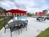 Inviting outdoor oasis with a sparkling pool, elegant patio furniture, and vibrant red umbrellas, perfect for relaxation.