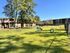 Bright and inviting apartment complex featuring a spacious fenced-in dog park with agility equipment and lush green lawns.