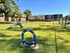 Inviting dog park with agility equipment in a sunny, fenced-in green space surrounded by charming brick apartment buildings.