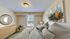 Cozy bedroom with elegant artwork, inviting bedding, and a stylish round mirror reflecting natural light through a large window.