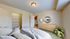 Bright, modern bedroom featuring cozy bedding, ample natural light, and elegant decor with a stylish dresser and a vibrant houseplant.