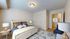 Inviting bedroom with a plush bed, elegant lamps, and a stylish blue accent chair, radiating comfort and tranquility.