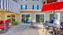 Charming outdoor patio area with elegant seating, vibrant red umbrellas, and lush greenery, perfect for relaxation and social gatherings.