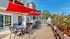 Charming patio with vibrant red umbrellas, stylish outdoor furniture, and a lush vegetable garden, ideal for relaxing afternoons.