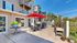 Inviting outdoor patio with modern seating, vibrant red umbrellas, and lush greenery, perfect for outdoor gatherings.