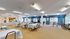Bright and spacious community dining area with inviting tables, vibrant blue accents, and abundant natural light through large windows.