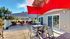 Inviting outdoor patio with vibrant red umbrellas, cozy seating area, and lush greenery, perfect for relaxation and entertaining.