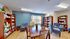 Inviting reading room with cozy blue chairs, elegant bookshelves filled with books, and a wooden dining table in a well-lit space.