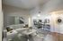 Modern open-concept living area with stylish decor, featuring a cozy sectional sofa, a sleek coffee table, and a kitchen bar with stools, ideal for entertaining.