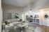 Modern open living space featuring a stylish sectional sofa, artistic decor, and a seamless transition to a contemporary kitchen and dining area.