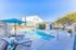 Inviting apartment pool area with cozy loungers, vibrant umbrellas, and a chic shaded seating nook, perfect for relaxation under a clear blue sky.