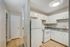 Modern kitchen with sleek white cabinetry, a spacious refrigerator, and stylish laminate flooring in a cozy apartment.