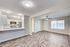 Modern open-concept living space featuring a sleek kitchen with stainless steel appliances and spacious living room with wood flooring.