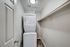 Compact laundry area featuring a modern stacked washer and dryer in a sleek, neutral-toned closet space.