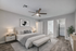 Elegant bedroom with modern decor, featuring a cozy bed, stylish ceiling fan, and a sleek attached bathroom with an in-unit washer and dryer.