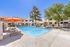 Inviting outdoor pool area with vibrant orange umbrellas, surrounded by lush greenery and modern apartments, perfect for relaxation and leisure.