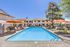 Inviting apartment complex pool area with bright orange umbrellas and lounge chairs, perfect for relaxation and enjoying sunny days.
