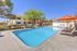 Inviting outdoor pool area with stylish lounge chairs and vibrant orange umbrellas, perfect for relaxation and social gatherings.