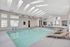 Elegant indoor swimming pool area featuring skylights and modern lounge chairs, perfect for relaxation and leisure.