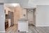 Modern kitchen with sleek stainless steel appliances, elegant grey countertops, and stylish subway tile backsplash, opening into a cozy living space.