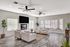Elegant living room with large windows, modern ceiling fans, and cozy seating arrangement. Features stylish decor and ample natural light for a welcoming ambiance.