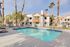 Charming apartment complex with a sunny outdoor pool area, chic lounge chairs, and beautiful palm trees, creating a perfect oasis for relaxation.