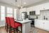 A stylish kitchen featuring white cabinets and vibrant red chairs, showcasing luxury living in Lusso Apartments, Columbus, Ohio.