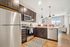 A stylish kitchen featuring mahogony cabinets and vibrant red chairs, showcasing luxury living in Lusso Apartments, Columbus, Ohio.