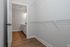 Spacious walk-in closet with sleek hardwood floors and ample shelving, adjacent to a modern bathroom with elegant vanity lighting.