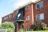 Inviting brick apartment building of River Annex, featuring lush green landscaping and modern architecture.