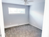 Bright bedroom with fresh white walls, plush carpeting, and a large window for natural light, ideal for relaxation.