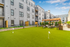Apartment complex amenity deck featuring a lush green putting area, stylish pergola seating, and modern landscaping.