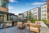 Chic outdoor lounge patio area with modern seating, barbecue grill, and lush landscaping in a stylish apartment complex.