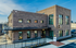 Modern brick building with sleek windows and inviting outdoor seating area, featuring the signage for Stella Leasing Office under a clear blue sky.
