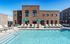 Inviting community pool area with modern lounge chairs and vibrant umbrellas, set against a stylish brick apartment building.