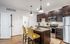 Modern kitchen featuring dark wood cabinets, stainless steel appliances, and a stylish granite island with yellow upholstered chairs.