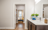 Modern bathroom with elegant fixtures and ample natural light leading to a cozy bedroom with stylish decor and a large window.