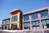 Charming commercial building with modern architecture, featuring large windows and attractive brickwork under a clear blue sky.